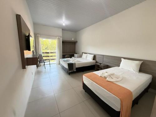 a hotel room with two beds and a table at Portal do Sol Lençóis Pousada in Barreirinhas