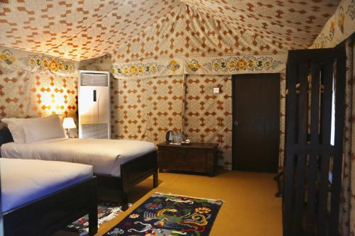 a bedroom with two beds and a wall with wallpaper at Haa Valley Camp in Kechungka