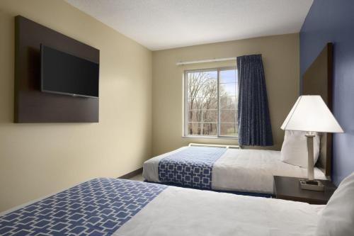 a hotel room with two beds and a window at Days Inn & Suites by Wyndham Cherry Hill - Philadelphia in Cherry Hill