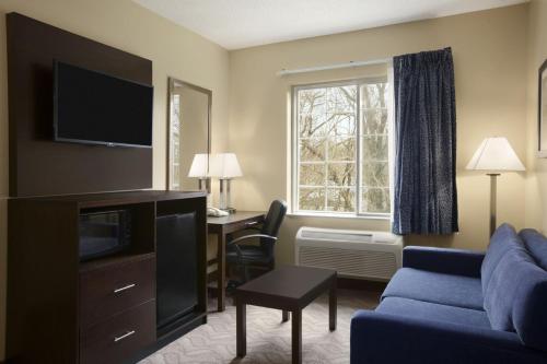 a hotel room with a couch and a desk and a window at Days Inn & Suites by Wyndham Cherry Hill - Philadelphia in Cherry Hill