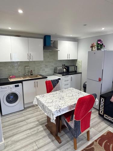 a kitchen with a table with red chairs and a refrigerator at Modern Studio in Newport City Centre Free Parking & WiFi Sleeps 2 in Newport