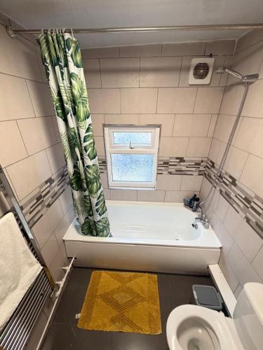 a bathroom with a tub and a toilet and a window at Modern Studio in Newport City Centre Free Parking & WiFi Sleeps 2 in Newport