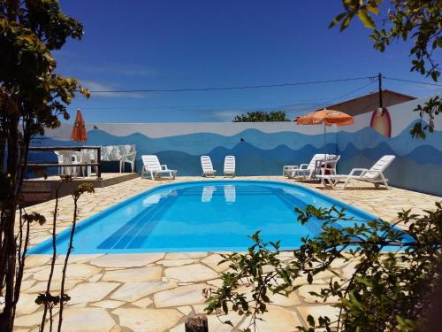 einen Pool mit Stühlen und einem Sonnenschirm in der Unterkunft Pousada Orla do Sol in Prado