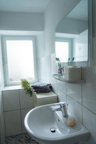 a white bathroom with a sink and a mirror at Elfriedes' Ferienhäuschen in Marktschorgast