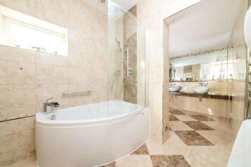 a bathroom with a tub and a toilet and two sinks at The Ayrlington Guesthouse in Bath