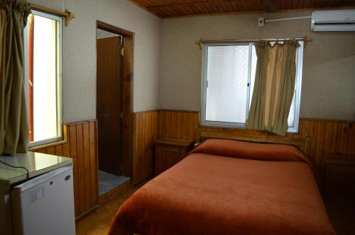 a bedroom with a bed and two windows at Hotel Tia in Salto