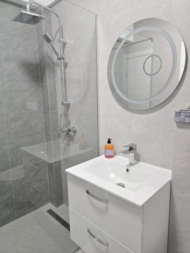 a bathroom with a sink and a shower with a mirror at Mountain View Studio in Piatra Neamţ