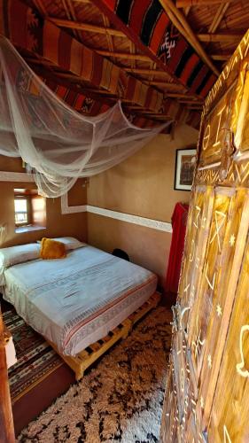 a bedroom with a bed with a mosquito net at Maison d'hôtes tilleli in Tamnougalt