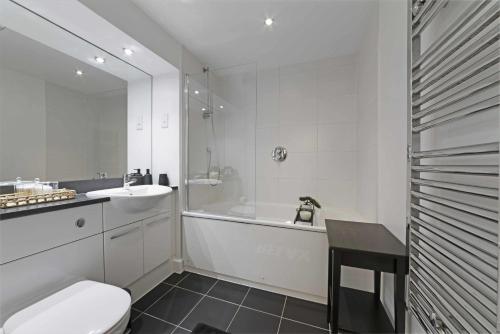 a bathroom with a toilet and a tub and a sink at Alaska apartmans in London