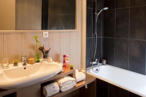 a bathroom with a sink and a bath tub at Hôtel Les Grillons in Talloires