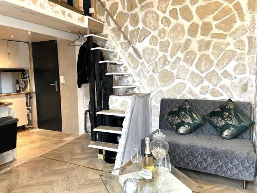 a living room with a couch and a stone wall at Charmant cocon, Lagny sur marne, parking, wifi, proche Disney RER in Lagny