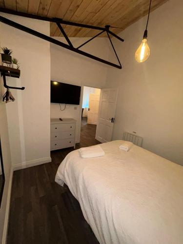 a bedroom with a white bed and a tv at The Stags Den in Longton