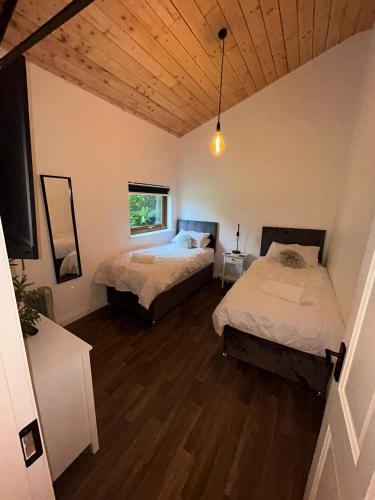 a bedroom with two beds and a wooden ceiling at The Stags Den in Longton