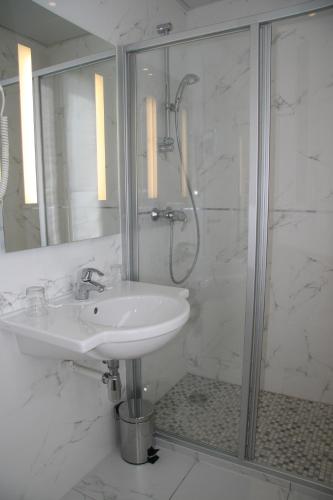 a white bathroom with a sink and a shower at Hotel Bellevue Saint-Lazare in Paris