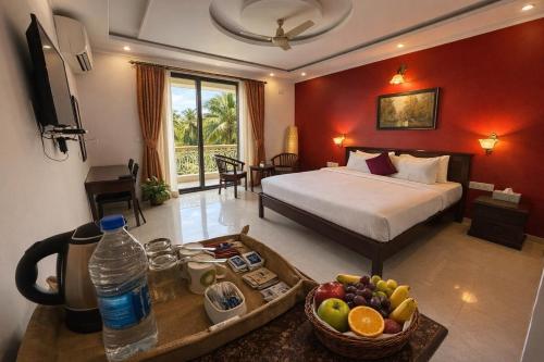 a hotel room with a bed and a tray of fruit at Praia Da Oura Boutique Resort ,Goa in Majorda