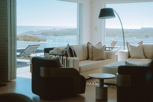 a living room with a couch and chairs and a large window at Jonesy's Place on the Beach in Yzerfontein
