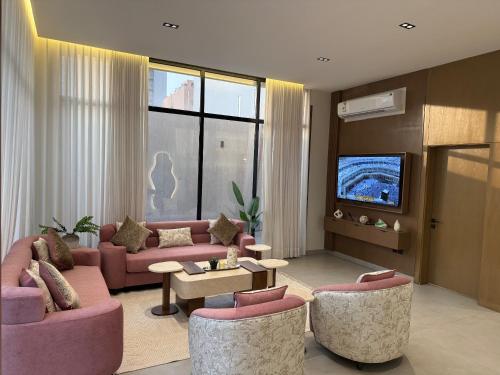 a living room with pink furniture and a flat screen tv at شاليهات بلانكا الفندقيه in Obhor