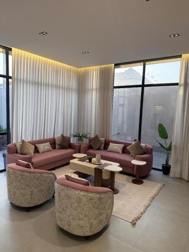 a living room with couches and tables and windows at شاليهات بلانكا الفندقيه in Obhor