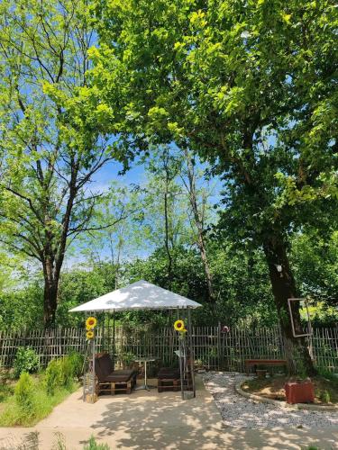 a table and chairs under an umbrella next to a fence at Campsite under two oaks in Itʼkhvisi