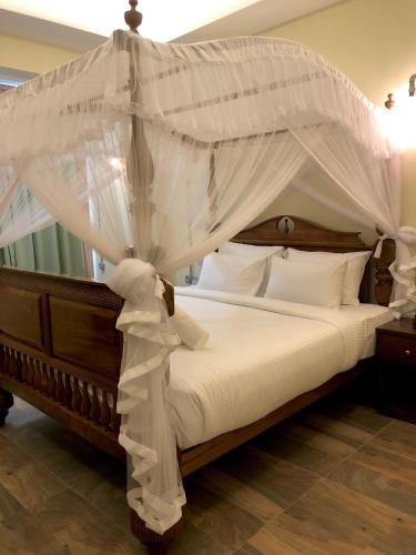 a bedroom with a canopy bed with white sheets and pillows at Kingswood Tea Factory in Ramboda