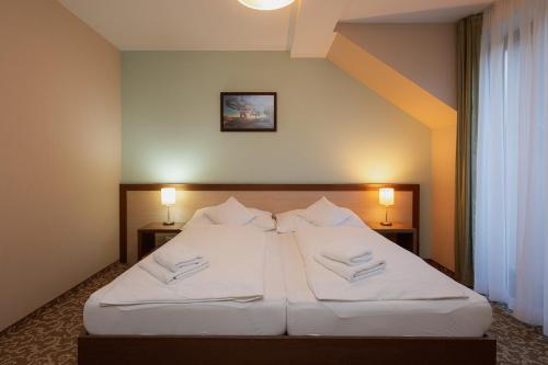 a bedroom with a bed with white sheets and pillows at Hotel Green in Dolný Kubín