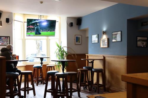a bar with stools and a tv on the wall at Harry's Hotel in Aberystwyth