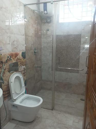a bathroom with a shower with a toilet and a glass door at Misty Hills in Yercaud