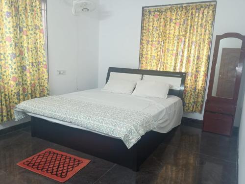 a bed in a bedroom with curtains and a red rug at Misty Hills in Yercaud
