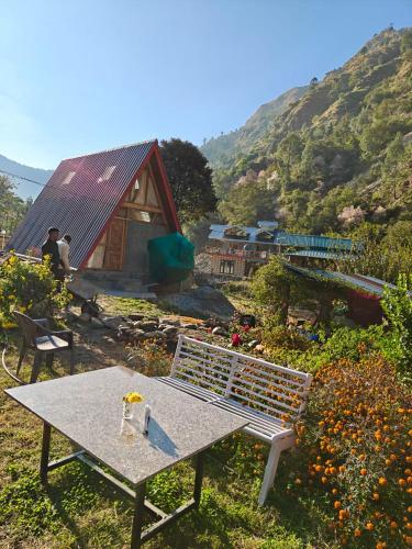 a bench and a table in a garden with a house at Nirvana River Nest in Sainj