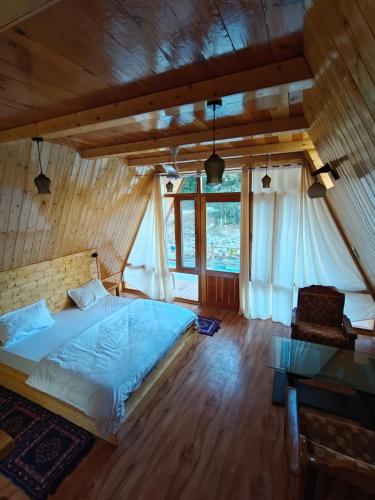 a bedroom with a bed and a large window at Nirvana River Nest in Sainj