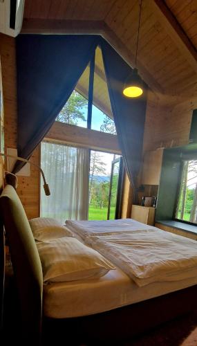 a large bed in a room with a large window at Pinja gozdne hiške in Črniče