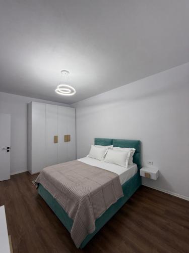 a bedroom with a large bed and a white wall at White Apartment in Kamëz