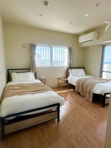 two beds in a room with two windows at アラハブルーリゾート in Chatan