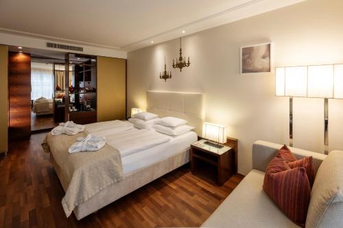 a bedroom with a large white bed and a couch at Boutique Hotel Das Tigra in Vienna