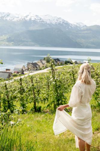 a woman in a white dress walking through a field at Charming tiny house with panorama view in Sandane