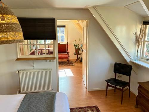 a bedroom with a bed and a chair in a room at LooSan Lodges Gastenhuis in Reutum