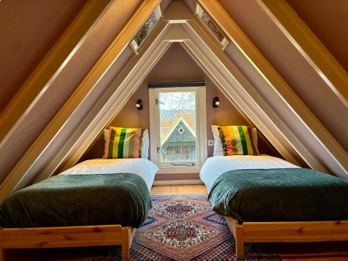 two beds in a room with a pointed ceiling at LooSan Lodges Gastenhuis in Reutum
