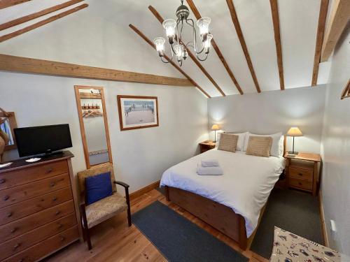 a bedroom with a bed and a tv in a room at All Seasons Cottage Breaks in Saxmundham