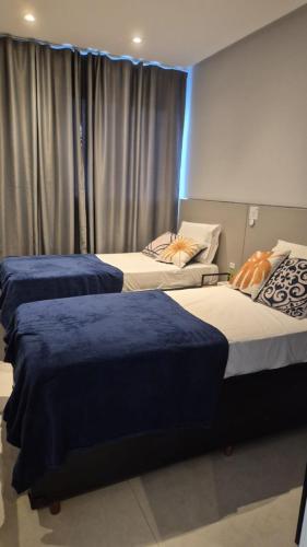 a room with three beds with blue covers on them at Nas Nuvens em Itaparica in Vila Velha