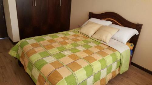 - une chambre dotée d'un lit avec une couverture verte et brune dans l'établissement Casa Vacacional, à Cuenca