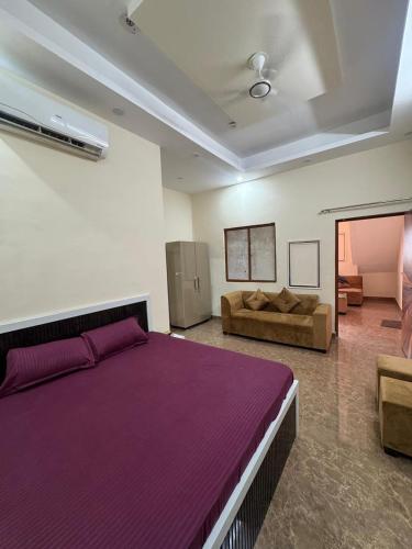 a bedroom with a large purple bed and a couch at Harmony House in Ghaziabad