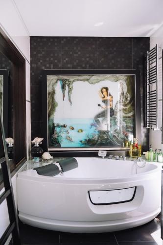 a bath tub in a bathroom with a painting on the wall at Royal Fraga do Douro in Vila Real