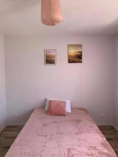 a bed in a bedroom with two pictures on the wall at Maison 2 chambre, salon, 5 couchage 57 rue du drain 95480 Pierrelaye in Pierrelaye