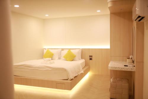 a bedroom with a white bed with yellow pillows at Kim Poshtel Hatyai in Hat Yai