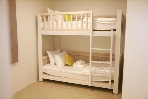 a bunk bed with white bunk beds in a room at Kim Poshtel Hatyai in Hat Yai