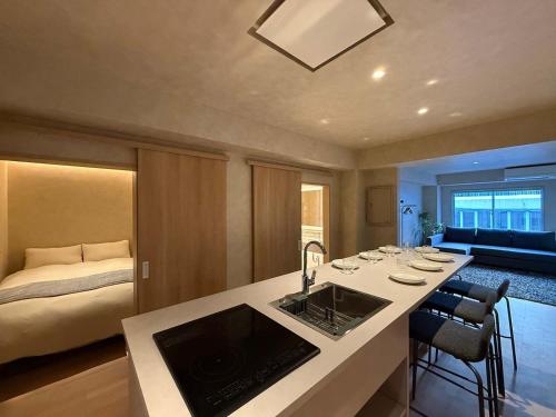 a kitchen with a sink and a room with a bed at Ishiki by b hotel - Next to Station Newly Renovated 3BR with Island Kitchen in Hiroshima