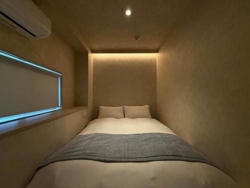 a small bed in a small room with a window at Ishiki by b hotel - Next to Station Newly Renovated 3BR with Island Kitchen in Hiroshima