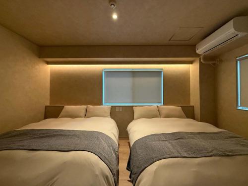 two beds in a room with a window at Ishiki by b hotel - Next to Station Newly Renovated 3BR with Island Kitchen in Hiroshima
