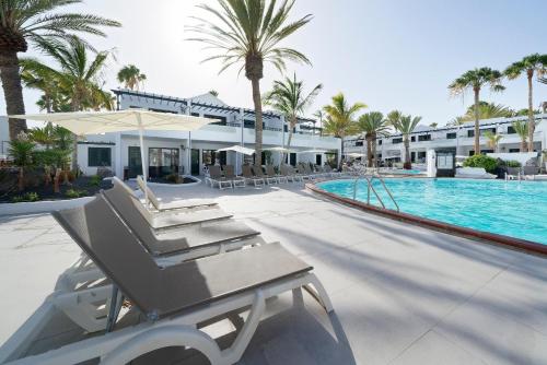 a resort swimming pool with chairs and a swing at BLUESEA Playa Club in Puerto del Carmen