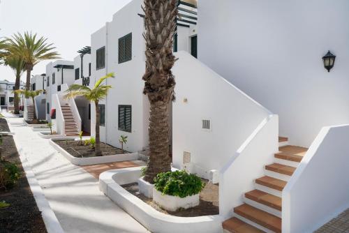 a white building with palm trees and stairs at BLUESEA Playa Club in Puerto del Carmen